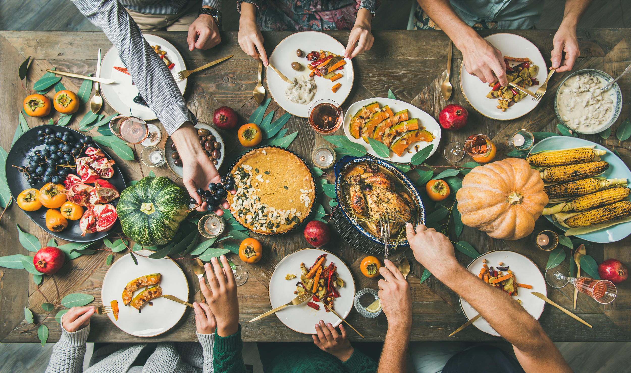 Friends feasting at Thanksgiving Day table with turkey, top view